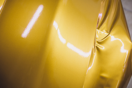 Car wrapping specialist putting vinyl foil or film on car wrapping protective film yacht, boat, ship, car, mobile home. yellow gold film hand pullsの写真素材