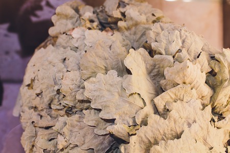 Bath accessories in traditional Russian sauna. Bath brooms from oak in wooden sauna bucket in the russian bath close up. Oak venik for banyaの写真素材