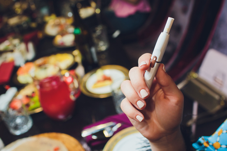 heat-not-burn tobacco product technology. Woman holding e-cigarette in his hand before smokingの写真素材