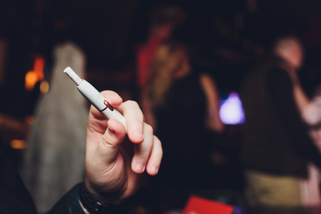 heat-not-burn tobacco product technology. Man holding e-cigarette in his hand before smoking.の写真素材