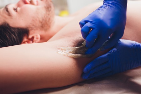 men sugaring hair removal armpit salon male.の写真素材