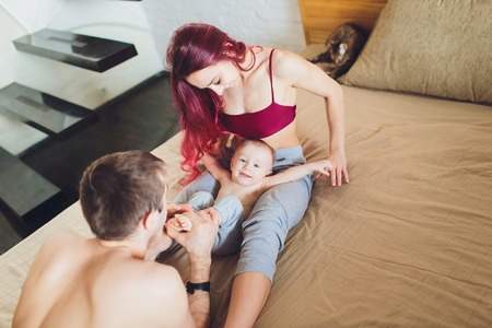happy young parents with baby in the bed at home.の写真素材