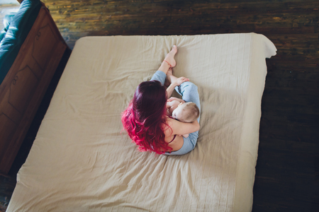 Young mother breastfeeding her newborn baby boy at home.の写真素材