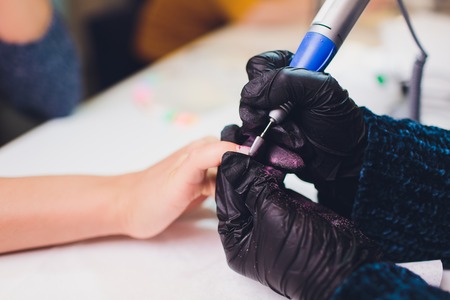 Hands in gloves cares about mans hand nails. Manicure beauty salon.の写真素材