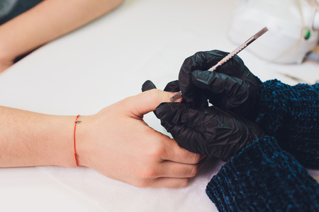 Hands in gloves cares about mans hand nails. Manicure beauty salon.の写真素材