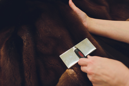 Dry cleaning business concept. Woman working with fur coat and brush.の写真素材
