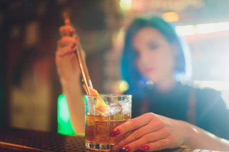 Female bartender spraying on the fresh delicious cocktail for serving it on the steel bar counter.の写真素材