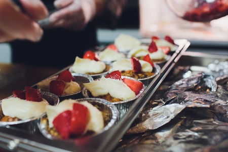 A chef decorates many plates of cake.