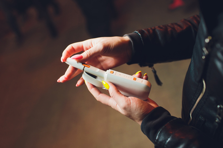 heat-not-burn tobacco product technology. woman holding e-cigarette in his hand before smoking.の写真素材