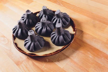 Black Georgian dumplings Khinkali with meat on white plate.