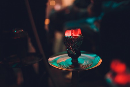 Shisha hookah with red hot coals. Sparks from breathe. Modern hookah with coconut charcoal for relax and shisha smoke. Hookah and sparks from coals. Another view. Shisha, spark,spark, hookah sparks.の写真素材