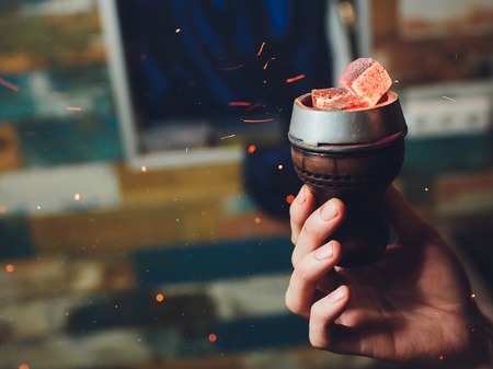 Shisha hookah with red hot coals. Sparks from breathe. Modern hookah with coconut charcoal for relax...