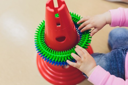 Children hand holding colorful of rubber cube and other shapes on wood texture backgroundの写真素材