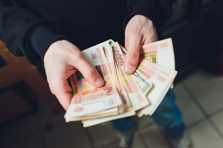 A man holds rubles and dollars in his hand, a businessman holds money in his hand.の写真素材