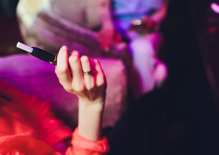 heat-not-burn tobacco product technology. woman holding e-cigarette in his hand before smoking.