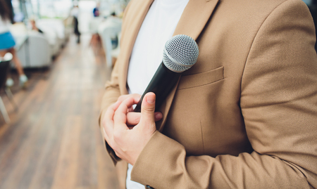 blurred of businessman hand holding microphone for speech presentation in conference hall, Seminar and Speaker Concept. vintage tone.の写真素材