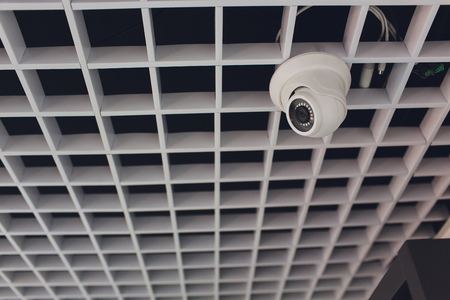 Security camera and motion detector installed on ceiling in roomの写真素材