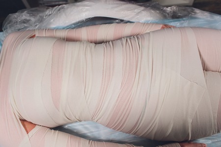 The cosmetologist wraps the leg of the customer. Anti-cellulite procedure-STYX wrap.