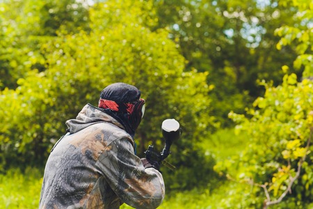 Paintball sport player in protective uniform and mask playing with gun outdoors.の写真素材