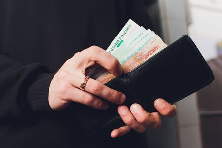 Hands take out russian rubles from wallet. Closeup on a mans hands as he is getting a banknote out of his wallet.の写真素材
