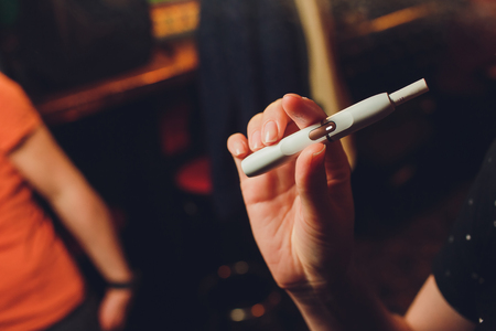heat-not-burn tobacco product technology. Man holding e-cigarette in his hand before smokingの写真素材