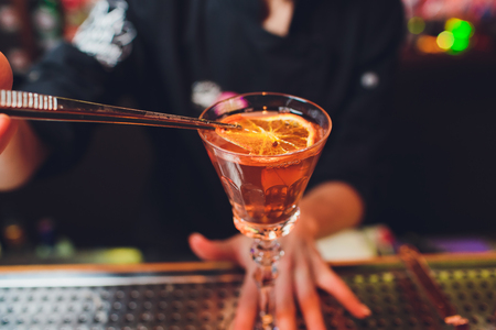 Glass of orange cocktail decorated with lemon at bar counter backgroundの写真素材