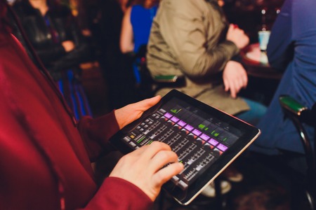 Event tuner controlling sound from tablet on the background of karaoke barの写真素材