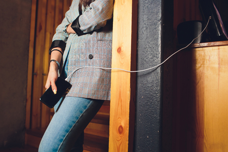 Girl using mobile phone while charging the batteryの写真素材