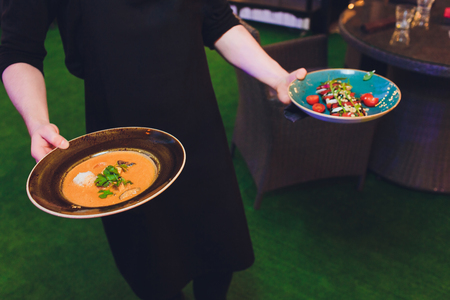 Waitress is carrying two plates with meat dishの写真素材