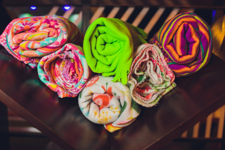 Stack of bath towels on light wooden background closeup.Pile of rainbow colored towels.Top view.Hygiene, fabric,spa and textile concept.bathroom accessoriesの写真素材