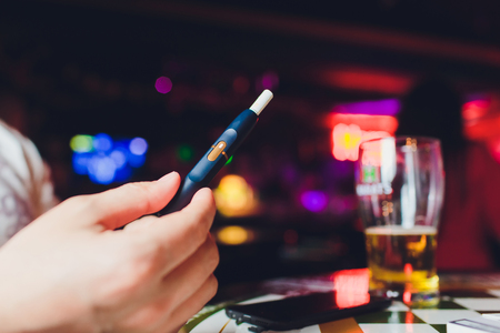 heat-not-burn tobacco product technology. Man holding e-cigarette in his hand before smokingの写真素材