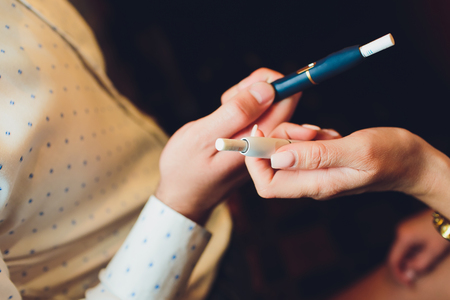 heat-not-burn tobacco product technology. woman holding e-cigarette in his hand before smokingの写真素材