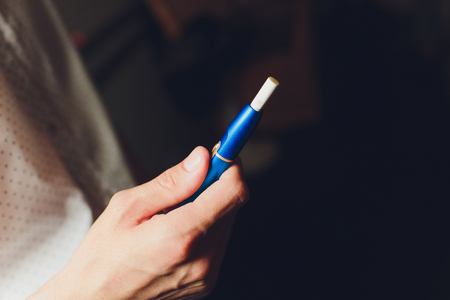 heat-not-burn tobacco product technology. Man holding e-cigarette in his hand before smokingの写真素材