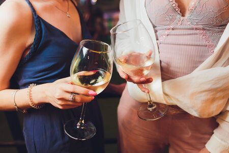Human hands with glasses of red wine clinking them over served table.の写真素材