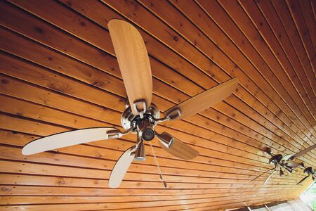ceiling fan on an exposed support beam, with a vaulted wood ceiling, in the living room of a modern home, with space for text on top and right side.の写真素材