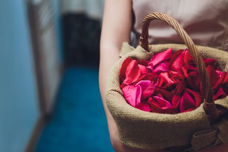 Bridesmaid in a white dress holding flower baskets for scattering rose petal at a wedding reception to church for a service of thanksgiving.の写真素材