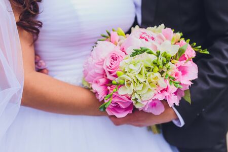 Beautiful wedding bouquet of flowers in the hands of the brideの写真素材