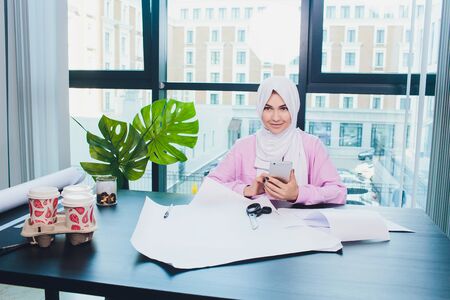 portrait of young attractive muslim woman fashion designer in her workshop smiling to camera.の写真素材