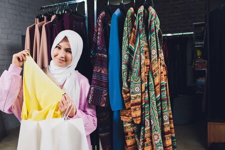Arab woman in traditional Muslim clothes buys a new dress in an Oriental store.の写真素材