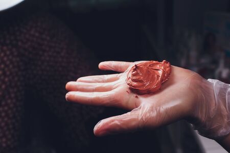 A woman makes a cosmetic mask of clay for healthy skin. In her hands she holds a cup and a stirring stick.の写真素材