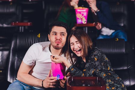 Young people sitting at the cinema, watching a movie and eating pop corn.の写真素材