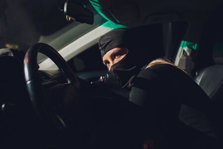 Masked robber woman car The thief is levering the lock at the door car robbery.の写真素材