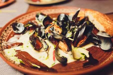 Close Up Still Life of Oysters with Cheesy Gratin Topping Served on Plate with Green Garnish on Painted Wooden Table with Copy Space.の写真素材
