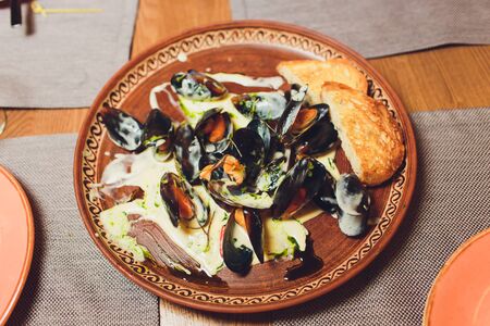 Close Up Still Life of Oysters with Cheesy Gratin Topping Served on Plate with Green Garnish on...