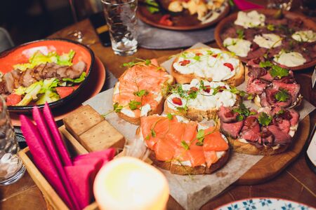 Appetizers table with italian antipasti snacks and wine in glasses. Brushetta or authentic traditional spanish tapas set, cheese variety board over grey concrete background. Top view, flat lay.の写真素材