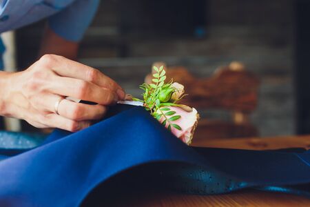 hand clings to the bridegroom a boutonniere of real flowers.