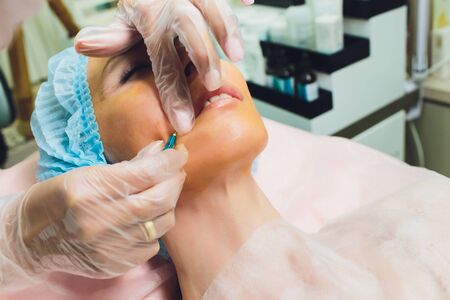 Close up of a hands threading beautiful womans upper lip.の写真素材