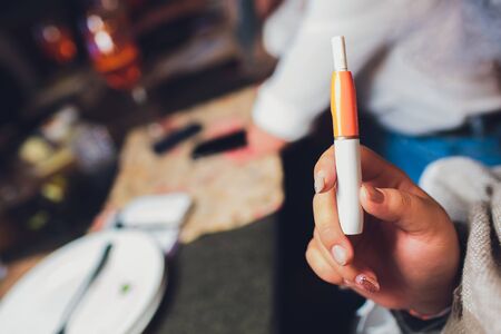 heat-not-burn tobacco product technology. woman holding e-cigarette in his hand before smokingの写真素材