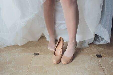 Bride in a beautiful wedding dress putting on shoesの写真素材