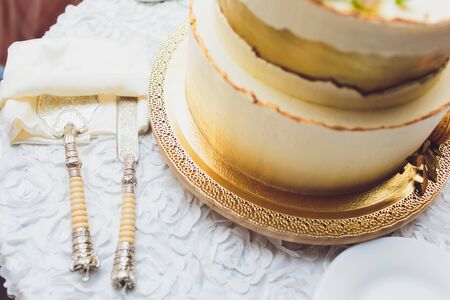 Three-tiered white wedding cake decorated with flowers from mastic on a white wooden table. Picture for a menu or a confectionery catalog with copy space.の写真素材